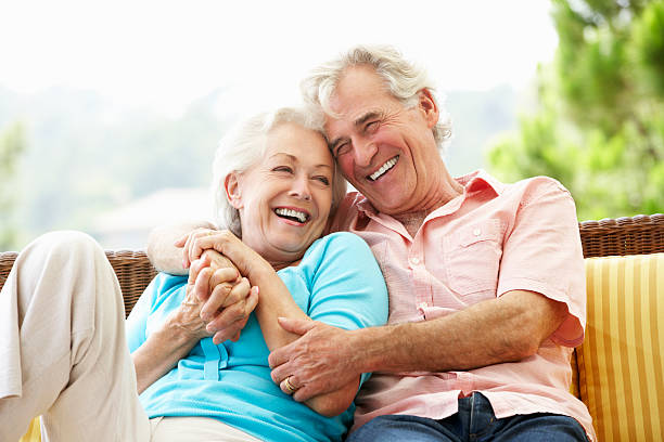 Happy elderly couple sitting together outdoors enjoying retirement by the shoreline